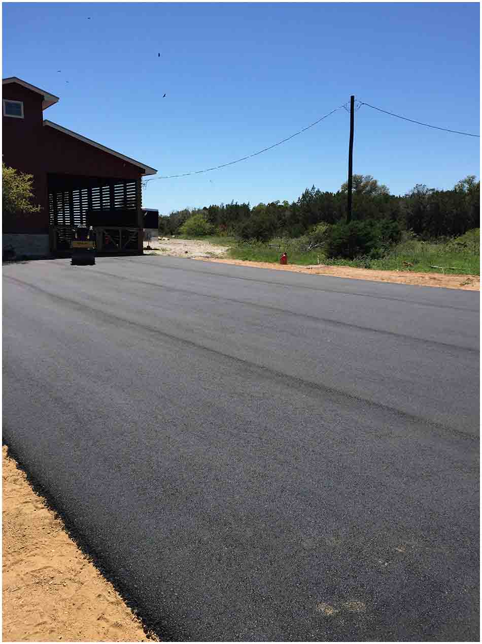 Completed asphalt surface beside a commercial or residential building