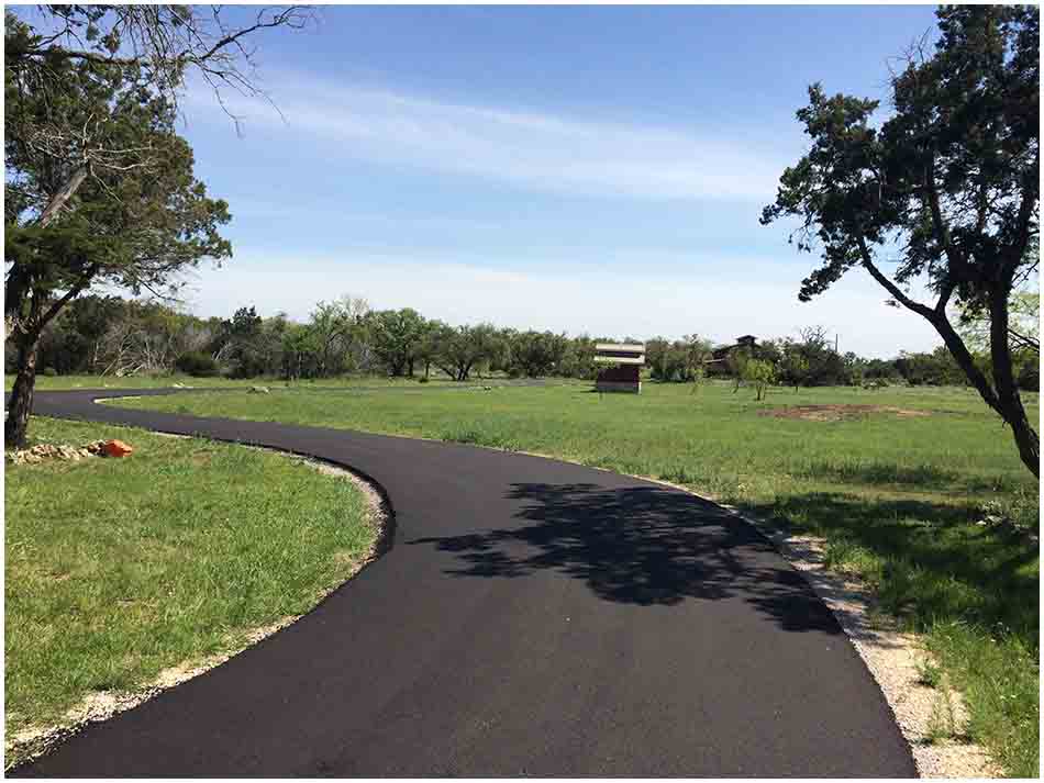 Completed curved asphalt driveway through a rural property