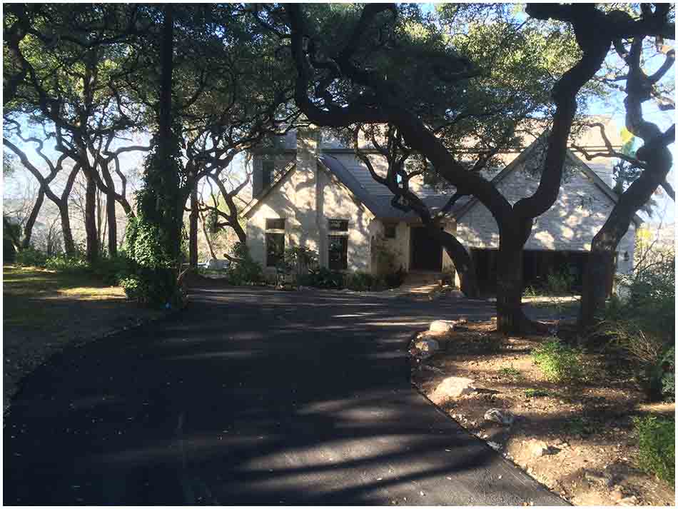 Completed asphalt driveway beneath mature oak trees