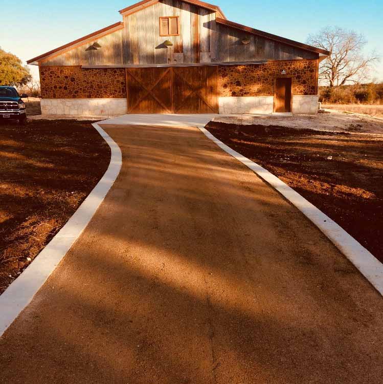 Crushed granite driveway with concrete borders leading to a barn