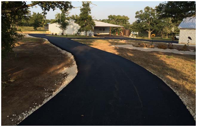 Completed asphalt driveway curving toward a Central Texas home